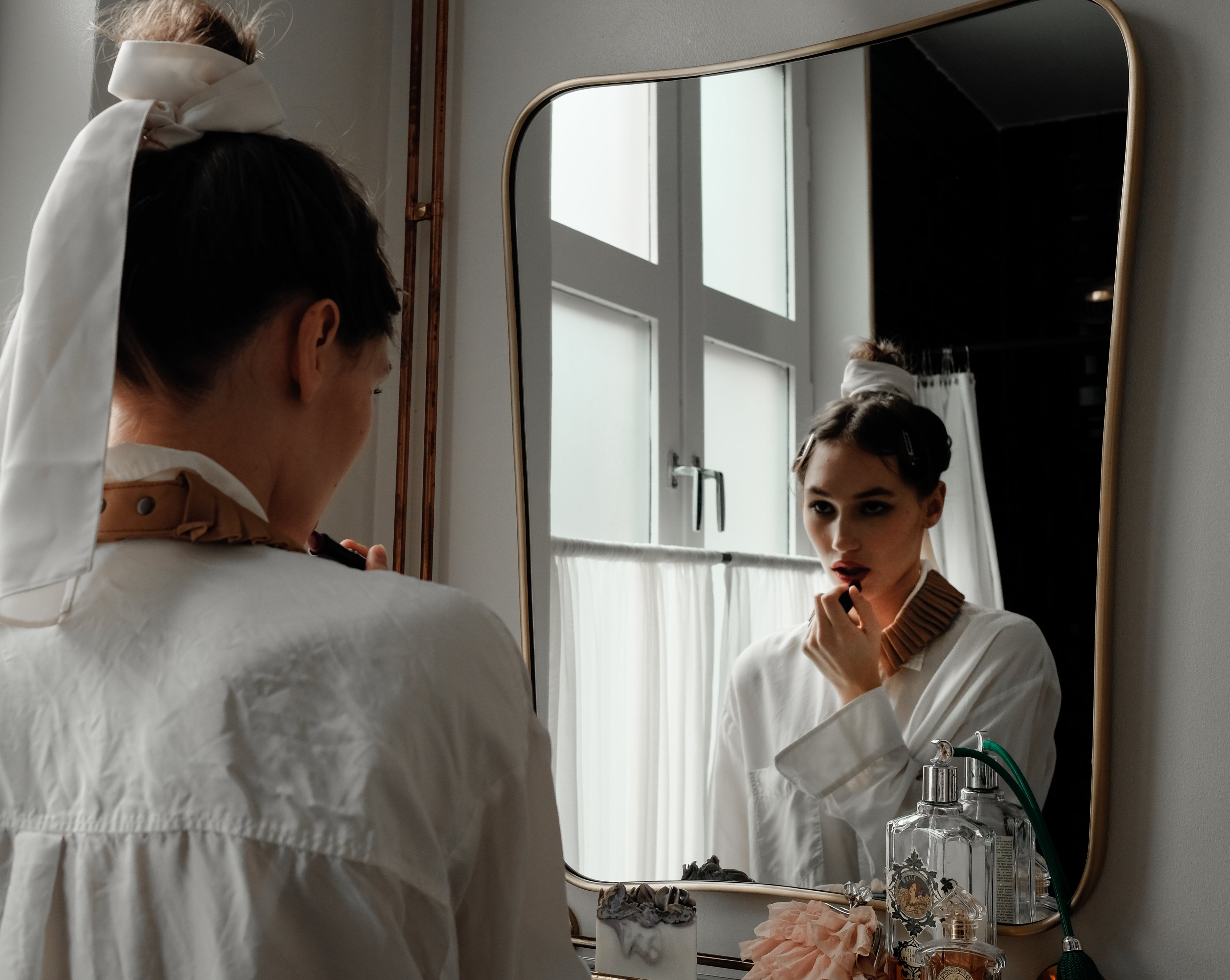 Denduon leather collar blooming dahlia on woman in white shirt in front of a mirror.