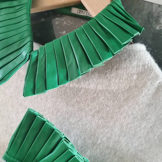 Denduon pleated leather collar and cuffs in green on a knitted sweater.