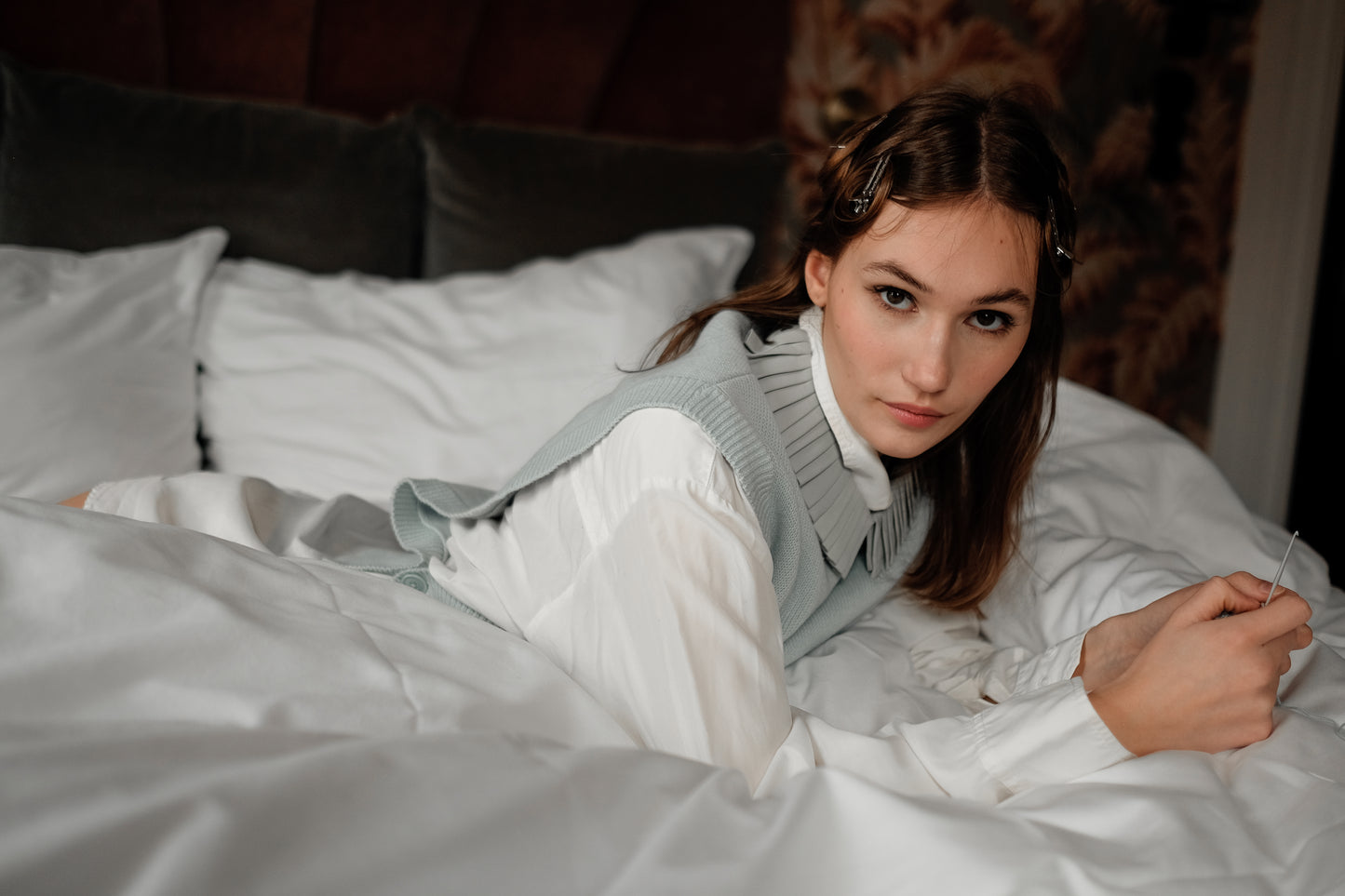 Denduon leather collar meadow mist on a woman laying on bed, wearing a white shirt and green slipver