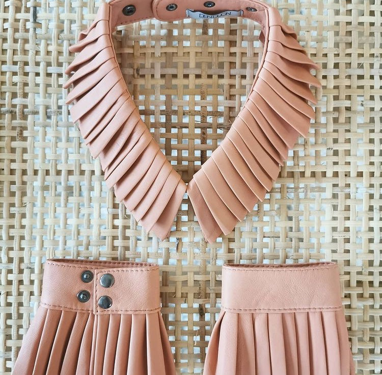 Pleated leather cuffs and collar in blooming dahlia on a rattan background.