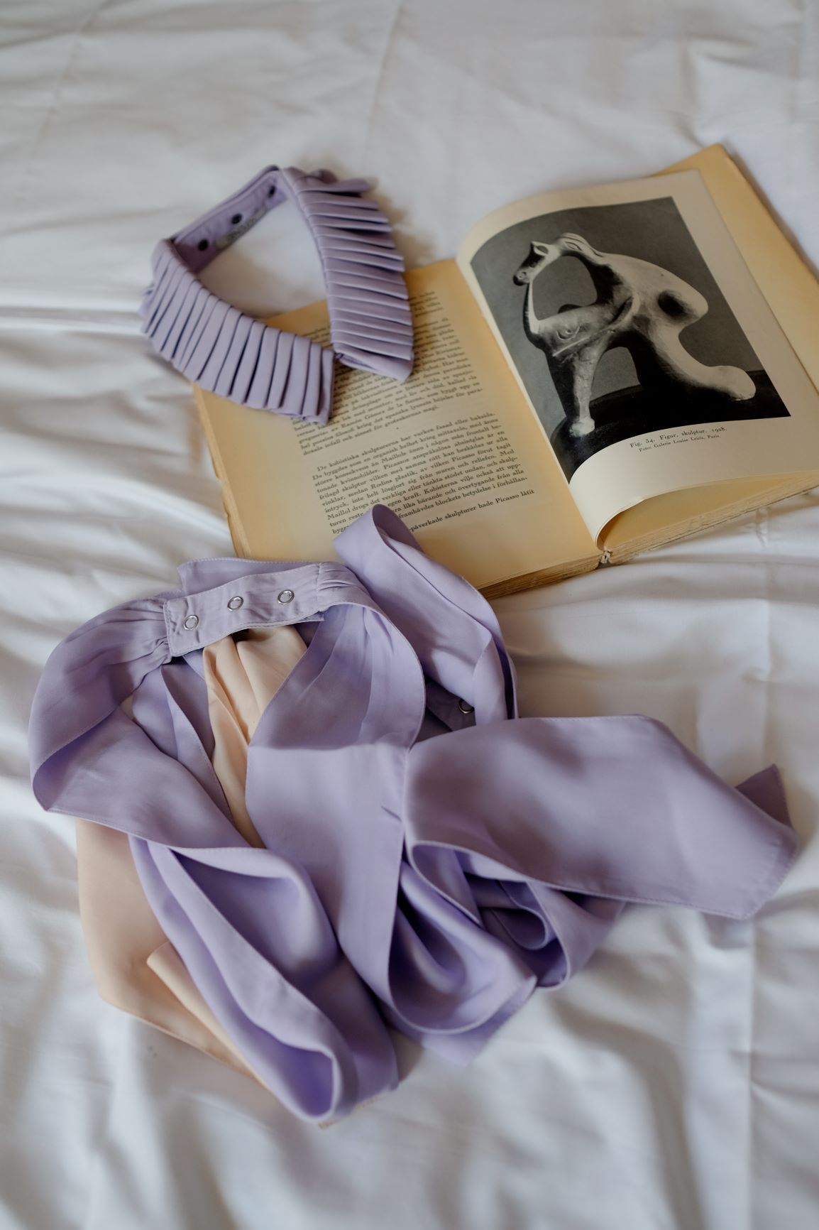 Lilac textile bow and collar on a book on hotel bed