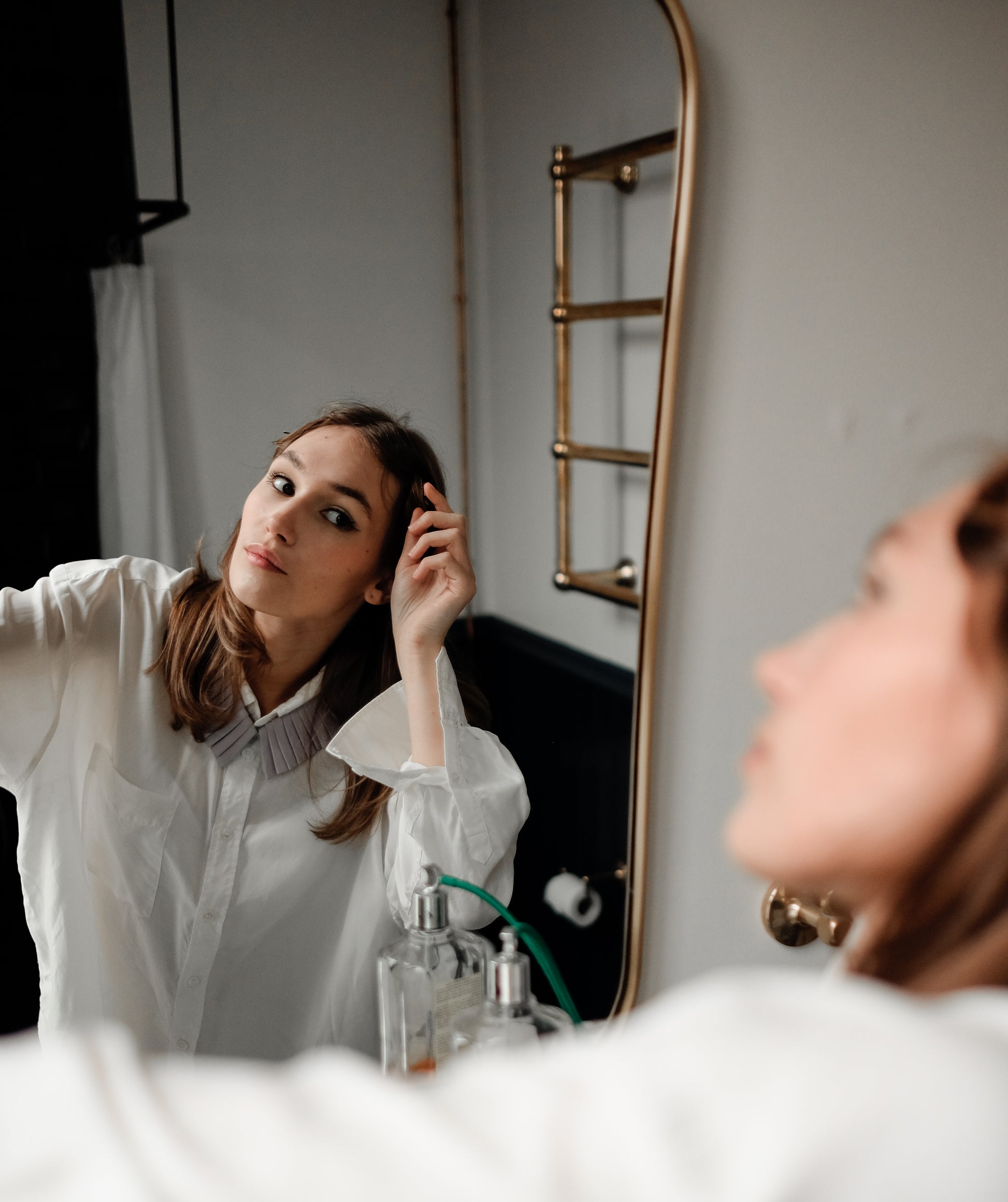 Denduon mushroom leather collar on woman with white shirt looking in mirror.