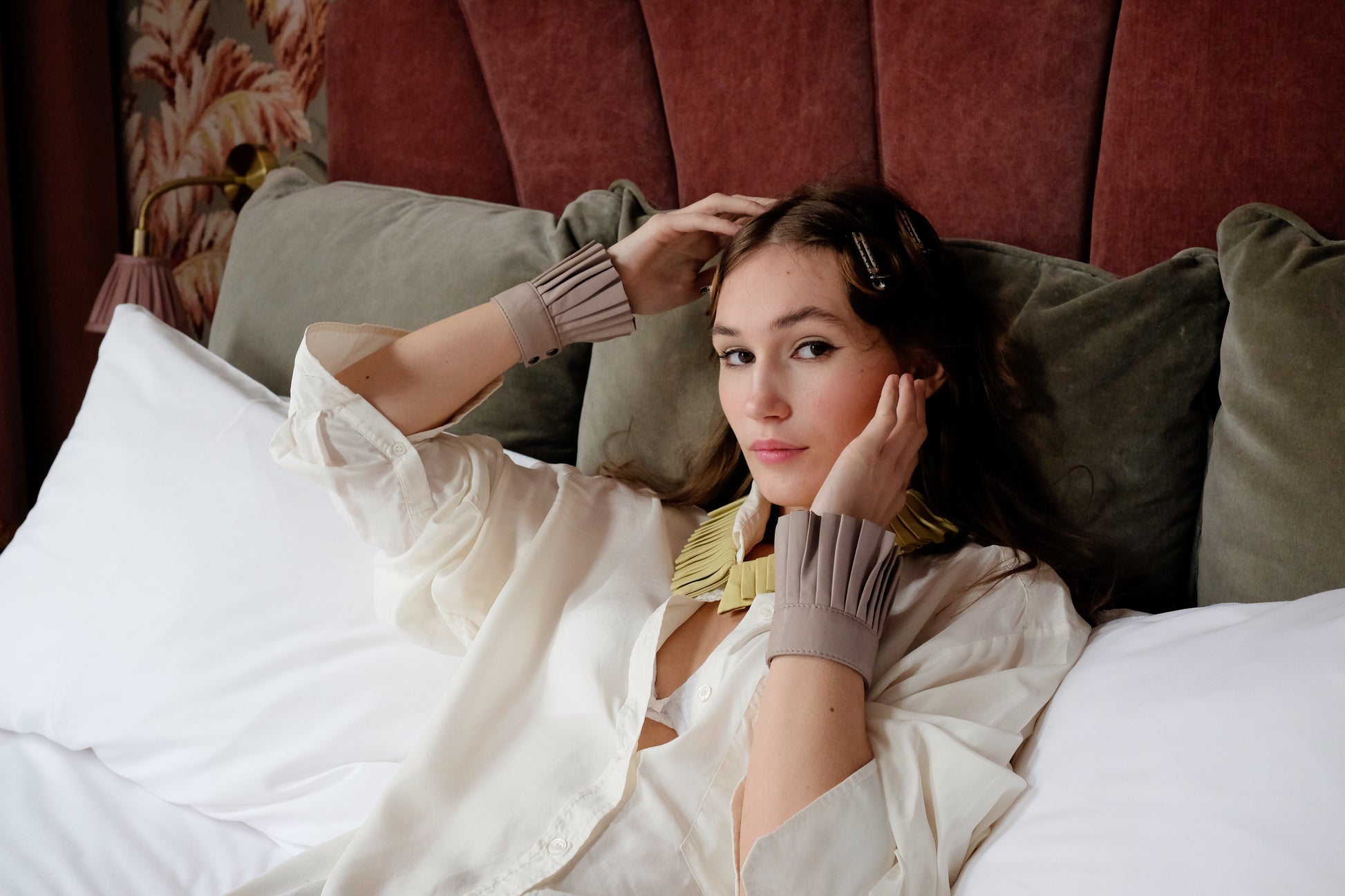 Denduon lemonade leather collar and mushroom cuffs on woman with white shirt laying on bed